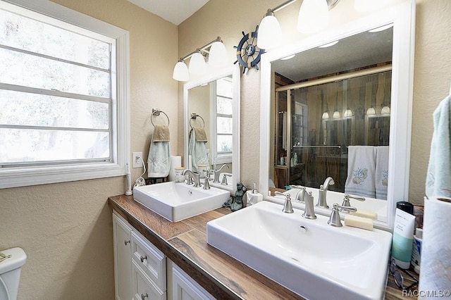 13920 W Evers Ct, Crystal River, FL 34429 - full bathroom with a textured wall, plenty of natural light, a shower with shower door, and double vanity