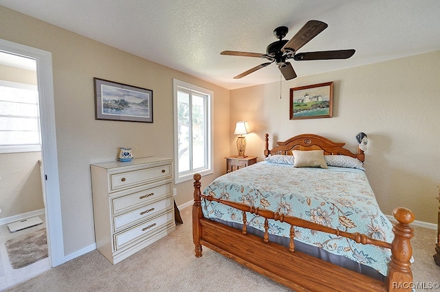 bedroom featuring a textured ceiling, light colored carpet, and ceiling fan