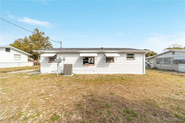 back of property with central air condition unit and a yard