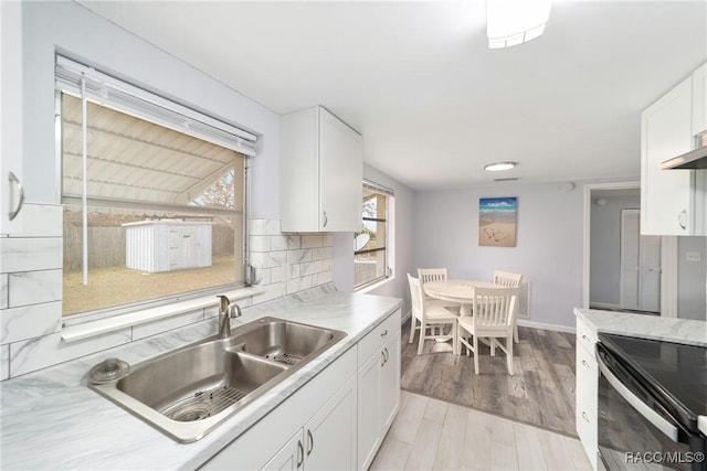 kitchen with backsplash, light hardwood / wood-style floors, electric range, sink, and white cabinetry