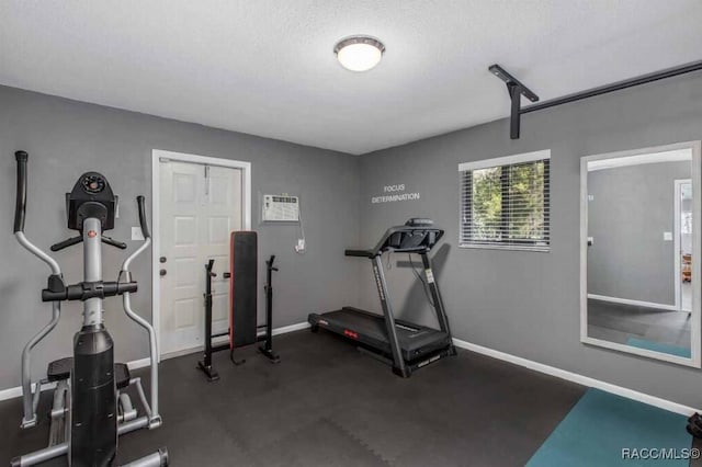 workout area featuring a wall mounted AC and a textured ceiling