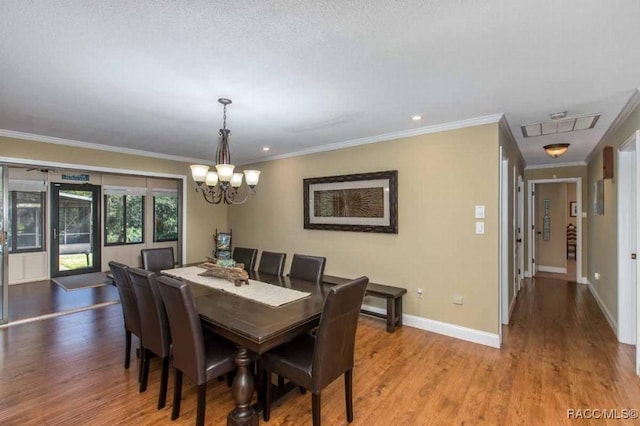 dining area with ornamental molding, a textured ceiling, a chandelier, and light hardwood / wood-style flooring