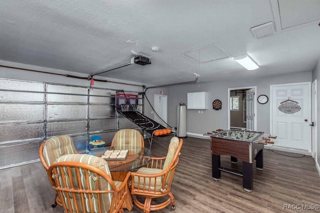 recreation room with dark hardwood / wood-style flooring, gas water heater, and a textured ceiling