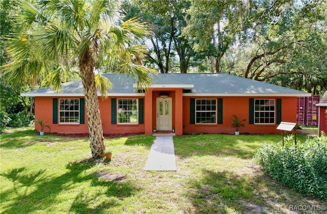 ranch-style home with a front yard and stucco siding