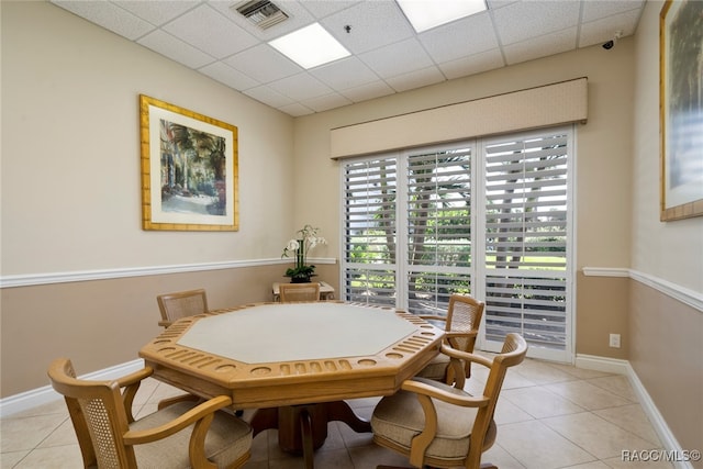 dining area with a drop ceiling and light tile patterned floors