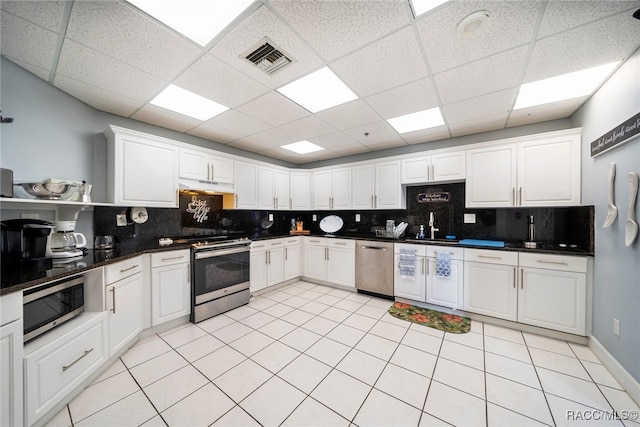 kitchen featuring appliances with stainless steel finishes, backsplash, a paneled ceiling, sink, and white cabinetry