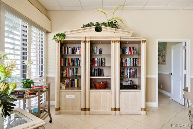 living area with a paneled ceiling, tile patterned floors, and a healthy amount of sunlight