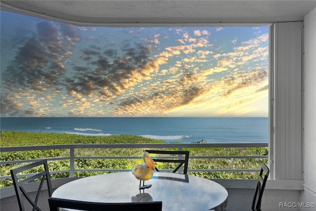 balcony at dusk featuring a water view