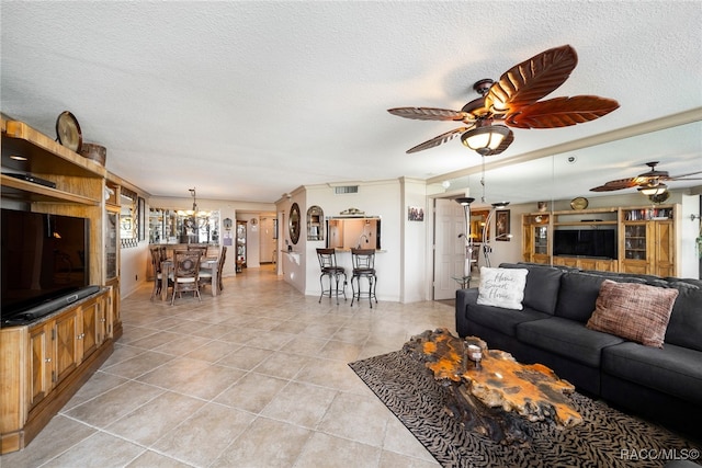 living room featuring light tile patterned floors, visible vents, a textured ceiling, and ceiling fan with notable chandelier