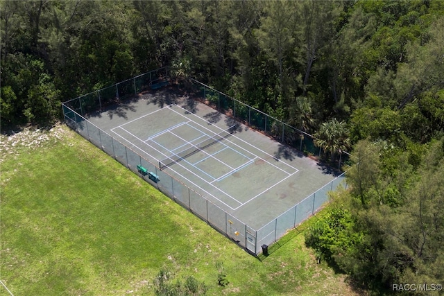 view of tennis court with fence and a lawn