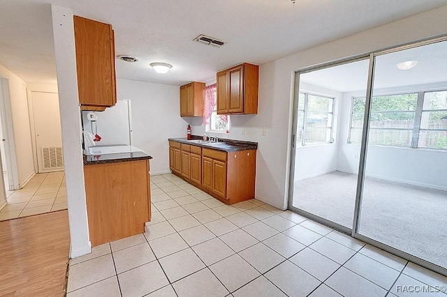 kitchen with a sink, visible vents, brown cabinets, and dark countertops