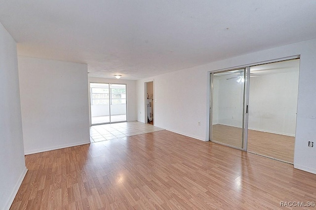 unfurnished bedroom featuring light wood-type flooring, baseboards, and a closet