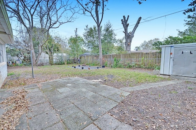 view of yard with a storage shed, an outbuilding, a fenced backyard, and a patio