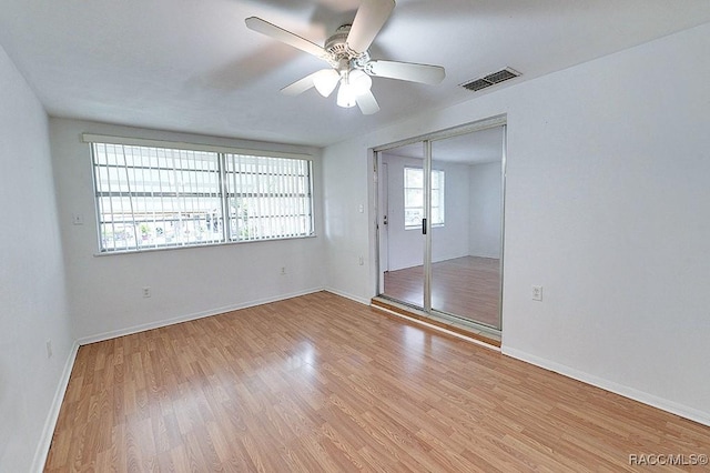 spare room featuring light wood-type flooring, visible vents, baseboards, and a ceiling fan