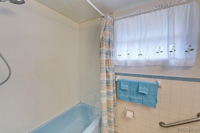 bathroom with shower / bath combination with curtain and tile walls