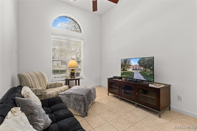 living area with baseboards, a ceiling fan, and light tile patterned flooring