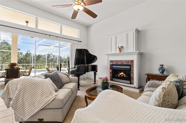 living room featuring a sunroom, ceiling fan, a fireplace, and light tile patterned floors