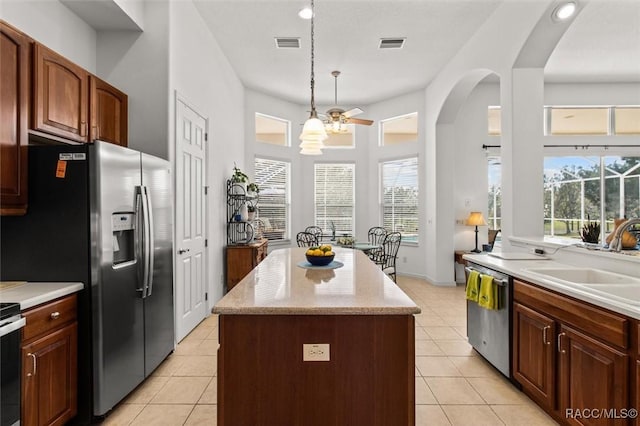 kitchen featuring light tile patterned floors, visible vents, a center island, stainless steel appliances, and a sink