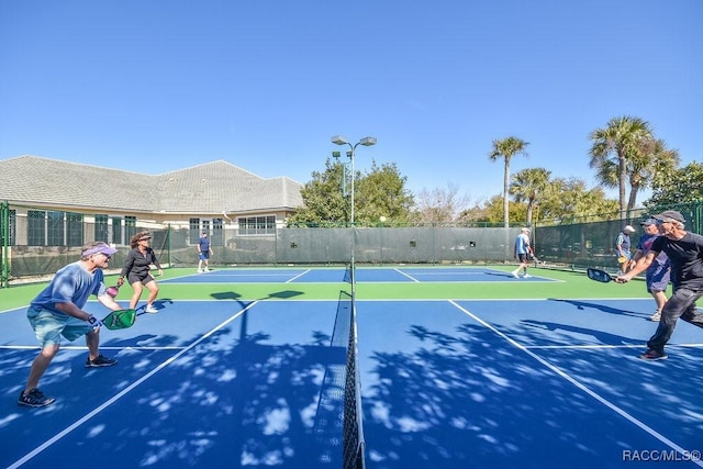 view of tennis court featuring community basketball court and fence