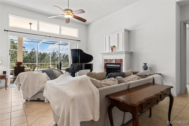 living room with ceiling fan, a fireplace, a high ceiling, and light tile patterned floors