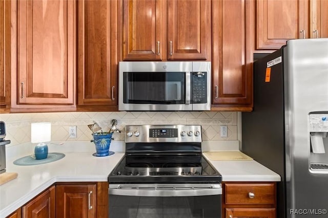 kitchen with brown cabinetry, appliances with stainless steel finishes, light countertops, and backsplash