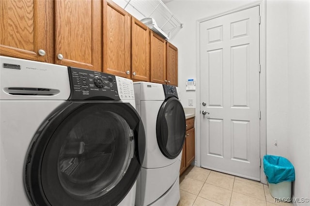 washroom with cabinet space, washing machine and clothes dryer, and light tile patterned flooring