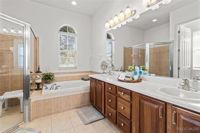 full bathroom featuring double vanity, a sink, tile patterned flooring, a shower stall, and a bath