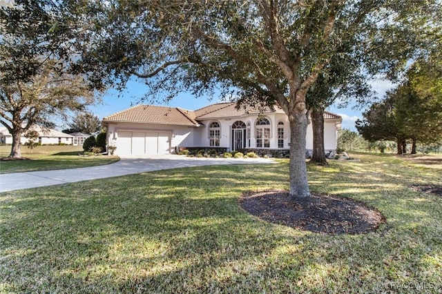 mediterranean / spanish-style home with a tile roof, stucco siding, an attached garage, a front yard, and driveway