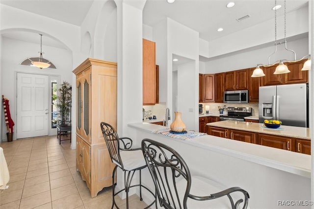 kitchen with stainless steel appliances, light countertops, visible vents, decorative backsplash, and light tile patterned flooring