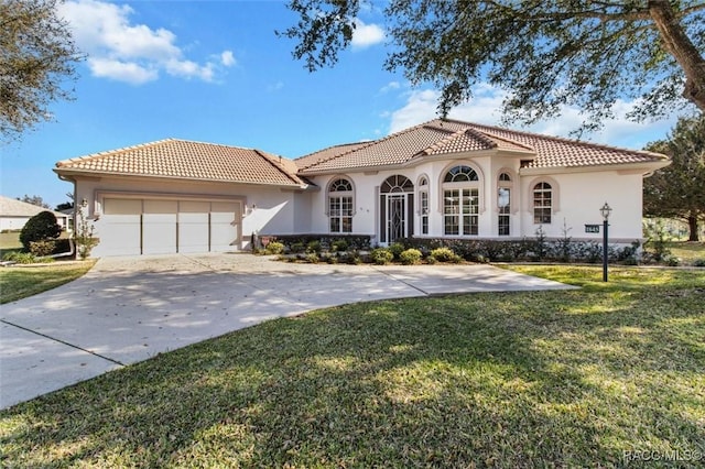 mediterranean / spanish home featuring an attached garage, a tile roof, driveway, stucco siding, and a front yard