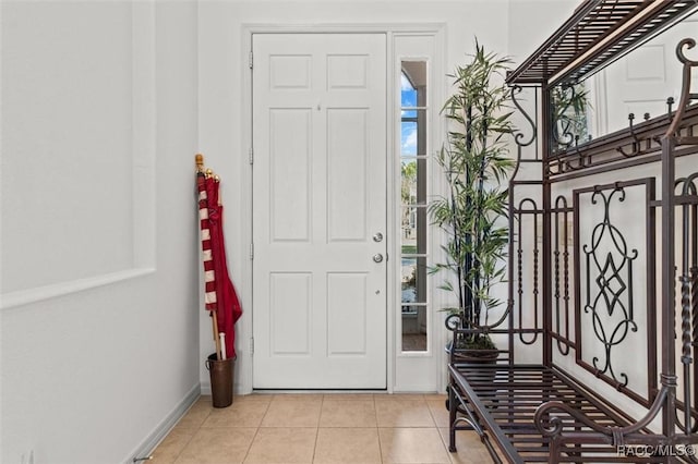 foyer entrance with light tile patterned floors and baseboards