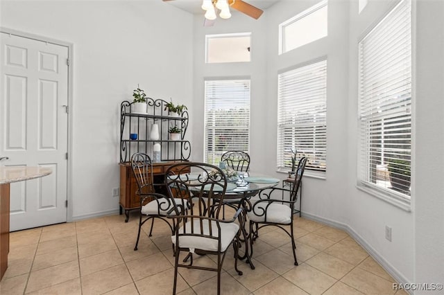 dining space with a ceiling fan, baseboards, and light tile patterned floors