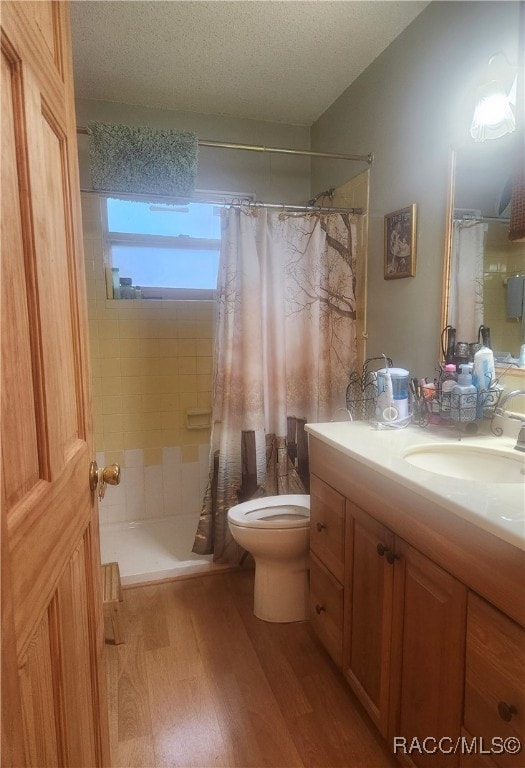 bathroom featuring walk in shower, hardwood / wood-style floors, a textured ceiling, toilet, and vanity