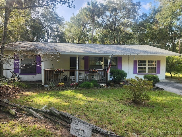 ranch-style home featuring covered porch and a front lawn