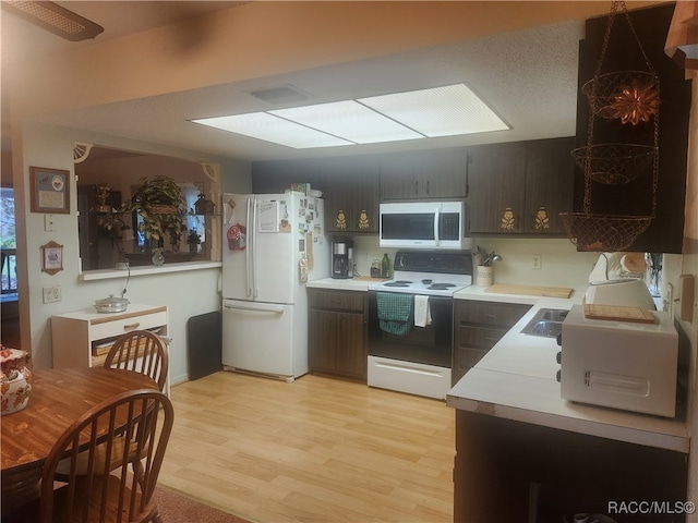 kitchen featuring white appliances, light hardwood / wood-style floors, dark brown cabinetry, and sink