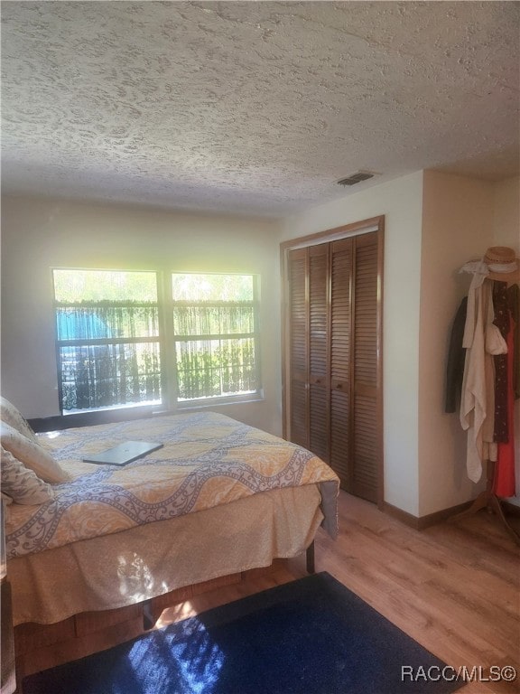 bedroom with hardwood / wood-style flooring, a textured ceiling, and a closet