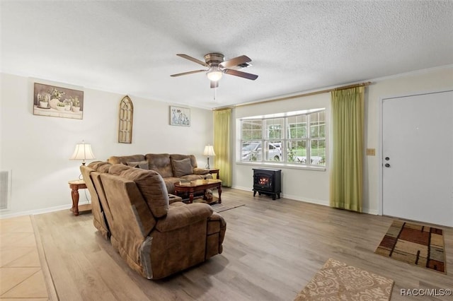 3550 S Dean Ter, Inverness, FL 34452 - living room featuring a wood stove, a ceiling fan, light wood-type flooring, and a textured ceiling
