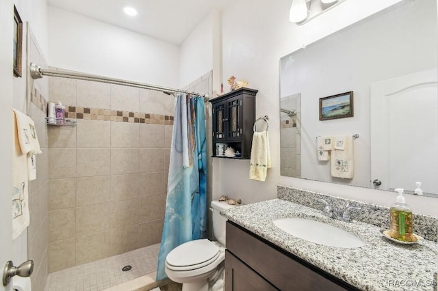 full bathroom featuring toilet, a tile shower, and vanity