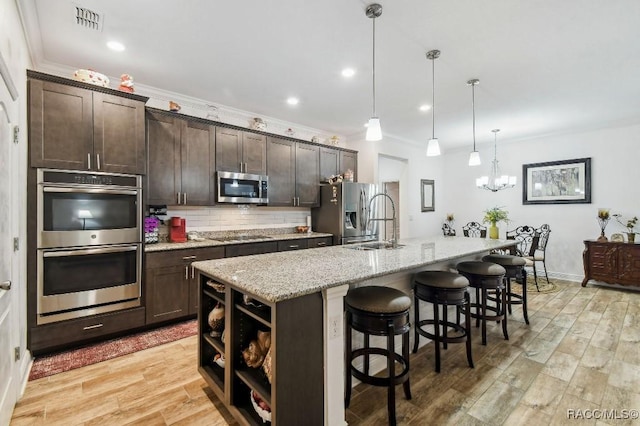 kitchen with dark brown cabinetry, visible vents, appliances with stainless steel finishes, and light wood-style flooring