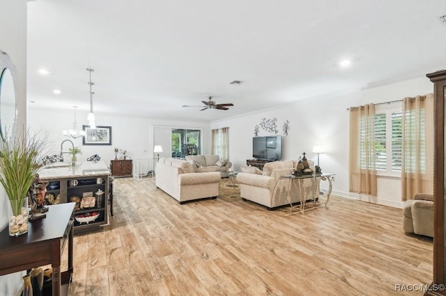 living room with light wood-type flooring, plenty of natural light, visible vents, and ornamental molding