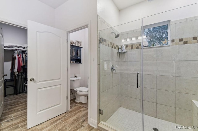 full bath featuring wood finish floors, toilet, and a stall shower