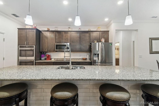 kitchen with appliances with stainless steel finishes, visible vents, dark brown cabinetry, and tasteful backsplash