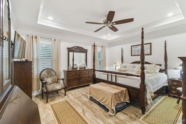 bedroom with a tray ceiling, recessed lighting, light wood-style floors, ornamental molding, and ceiling fan