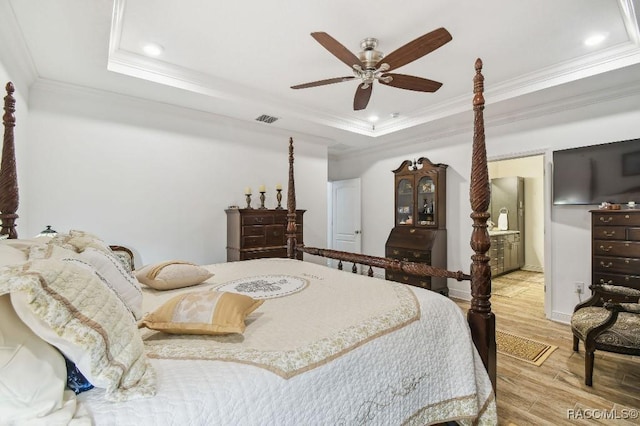 bedroom featuring recessed lighting, wood finished floors, visible vents, a tray ceiling, and crown molding