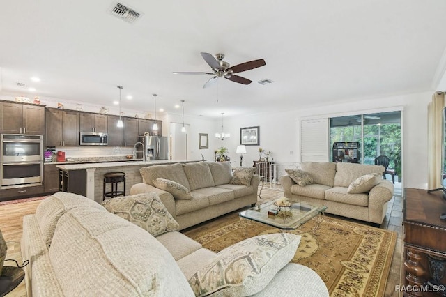 living room featuring ceiling fan with notable chandelier, visible vents, and recessed lighting