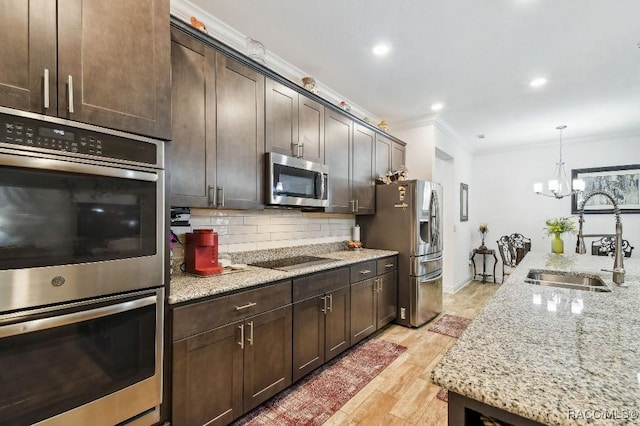 kitchen featuring a sink, dark brown cabinets, appliances with stainless steel finishes, backsplash, and crown molding