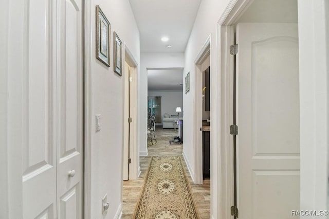 corridor with light wood finished floors and baseboards