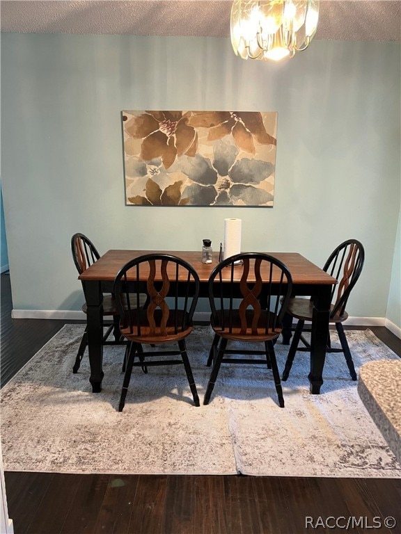 dining area with wood-type flooring, a textured ceiling, and a notable chandelier