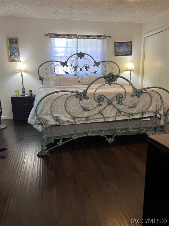 bedroom with a closet, hardwood / wood-style floors, and a textured ceiling