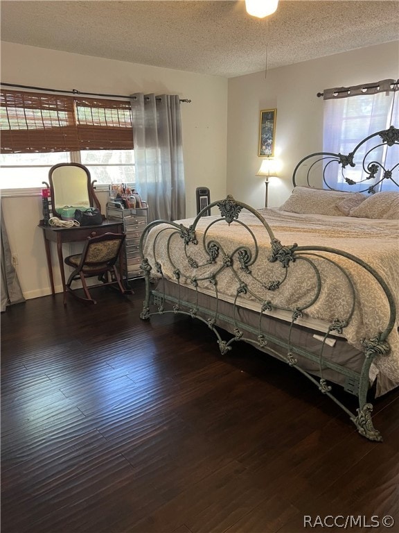 bedroom with a textured ceiling and dark wood-type flooring